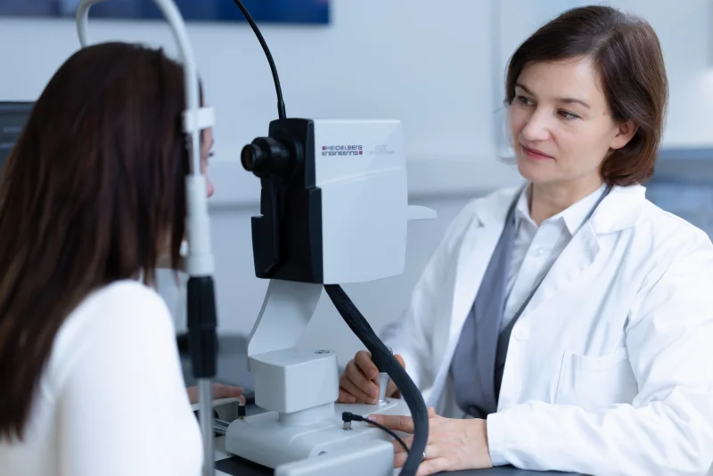 Oftalmološki pregled z uporabo slit lamp mikroskopa med zdravnico in pacientko